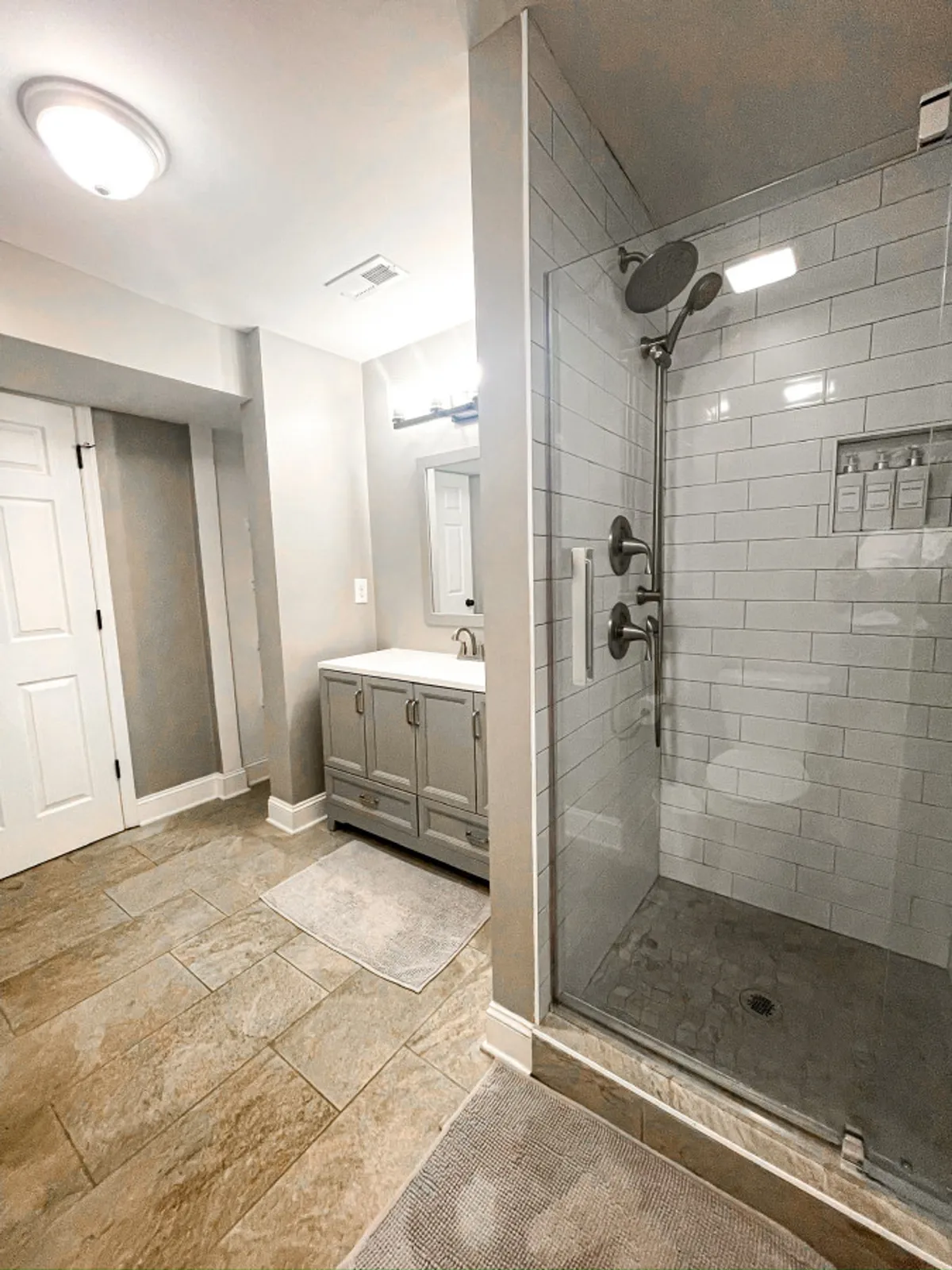A serene bathroom featuring a walk-in shower, vanity with sink, and a large mirror. The neutral palette and morning light create a spa-like ambiance ideal for relaxation and rejuvenation.