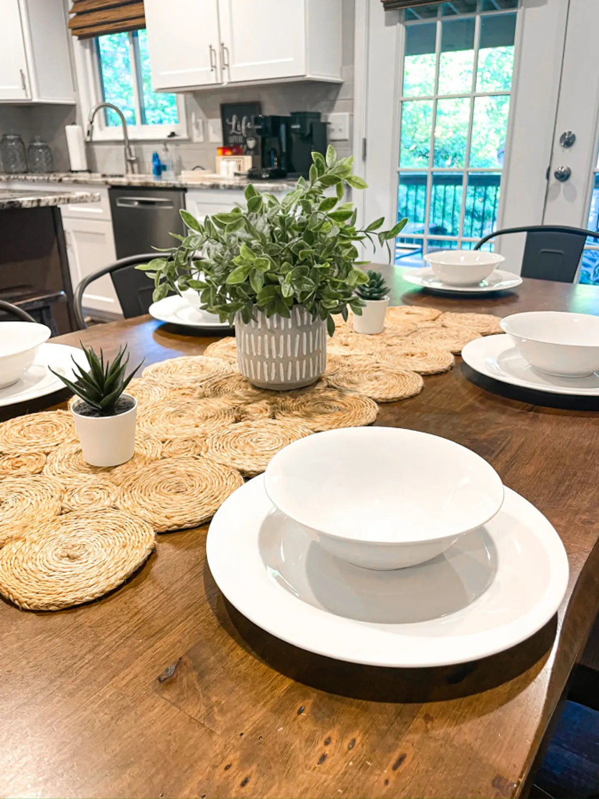 A thoughtfully set dining table is accented by tableware, potted plants, and woven placemats. The scene radiates warmth and connection, inviting guests to gather for meals, games, or celebrations.