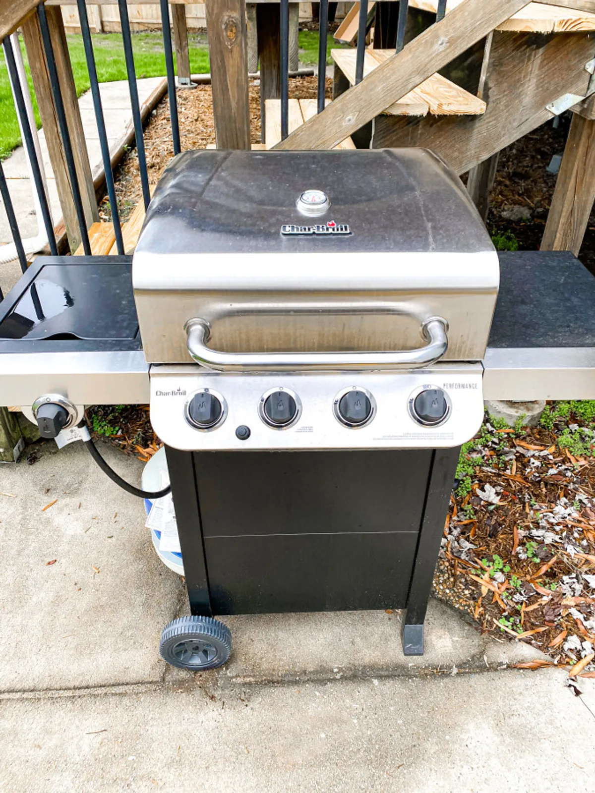 A Charbroil grill set beside a wooden structure on a concrete patio, ready for barbecuing. The surrounding area is spacious, hinting at ample room for group cookouts and outdoor meals.