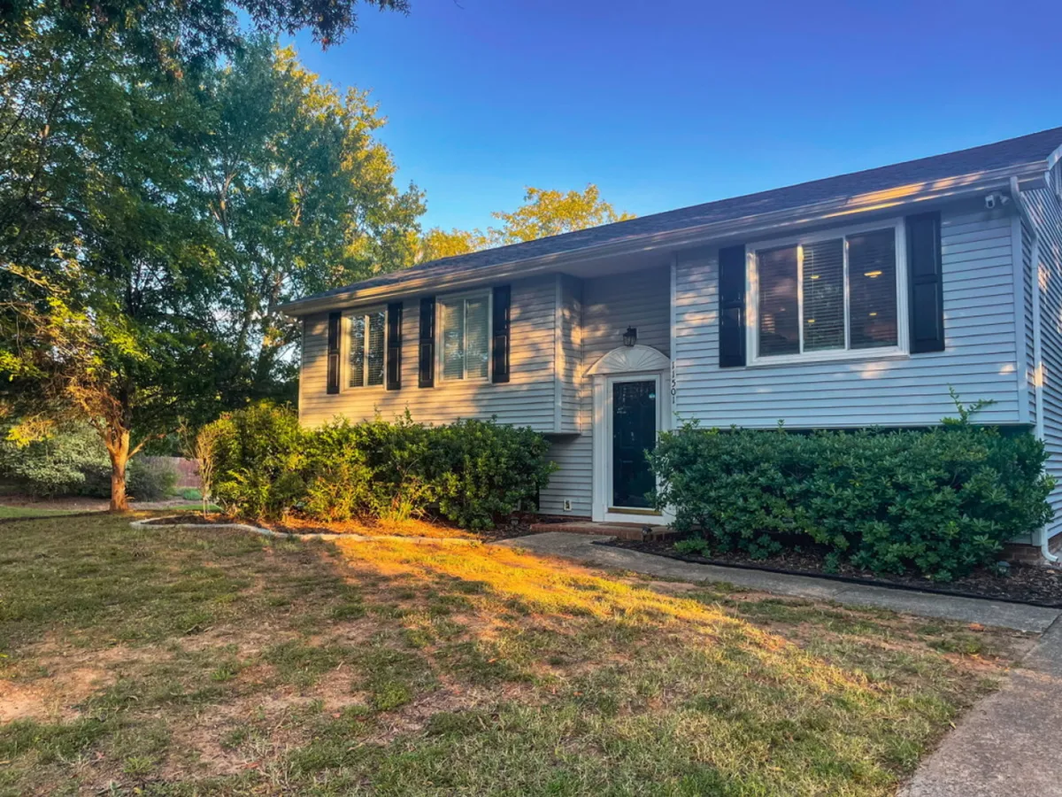 An inviting view of the home's front entrance and landscaped yard, highlighted by large windows and greenery. The setting is open and welcoming, suggesting easy access to nearby attractions and a sense of arrival for guests seeking adventure.