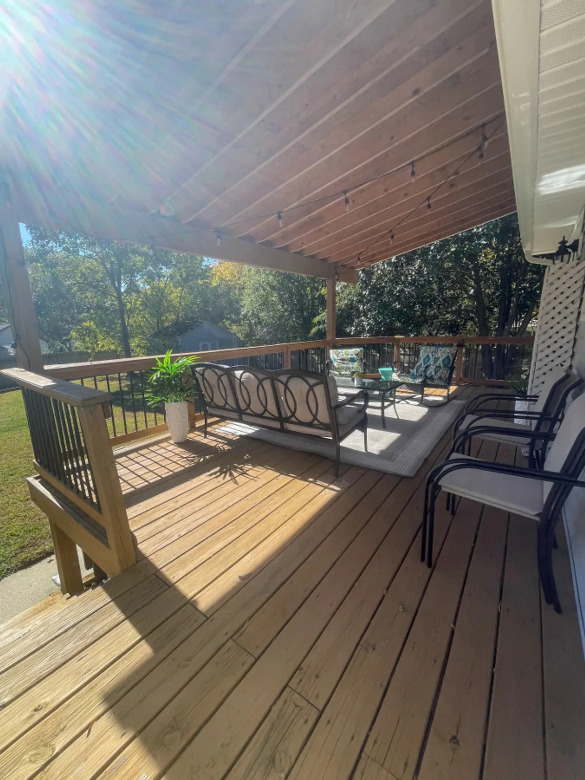A stylish outdoor seating area with comfortable chairs, decorative cushions, and a potted plant. The scene is bright and welcoming, indicating a space for relaxation, informal meetings, or enjoying a morning coffee before heading to work.